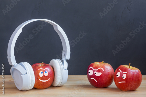 Photographie One apple in wireless headphones listening to music, two apple envy him