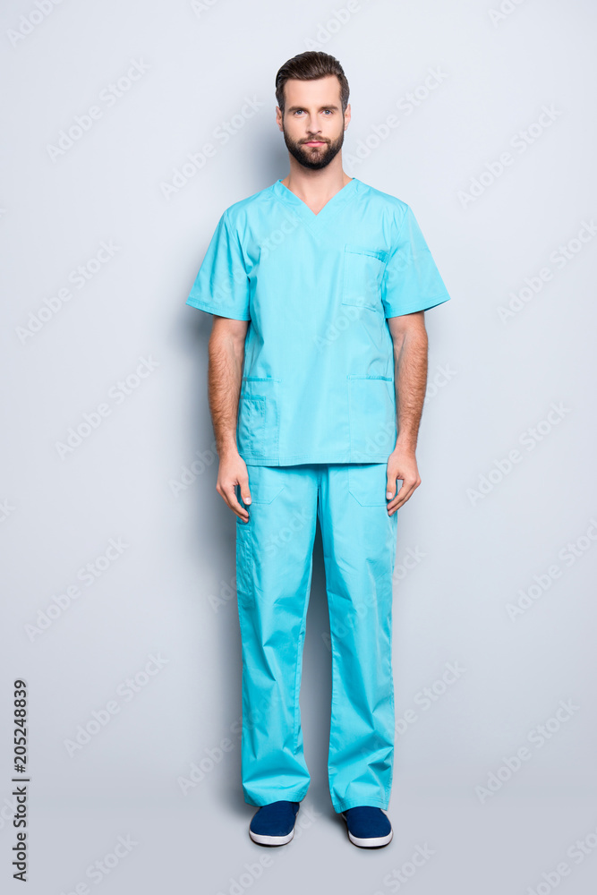 Full size body portrait of virile harsh man with bristle, hairstyle in blue lab suit, looking at camera, isolated on grey background Full size body portrait of virile harsh man with bristle, hairstyle in blue lab suit, looking at camera, isolated on grey background