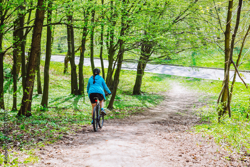 young woman ride bicycle in forest by trail © phpetrunina14