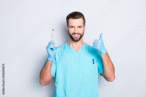 Obraz na plátně Portrait of joyful cheerful dental assistant in lab blue uniform gesturing thumb