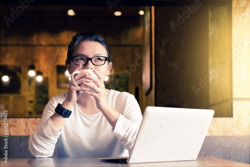 Asian charming beautiful girl freelancer thinking about new ideas or dreaming about something and drinking coffee in modern working room or coffee shop.