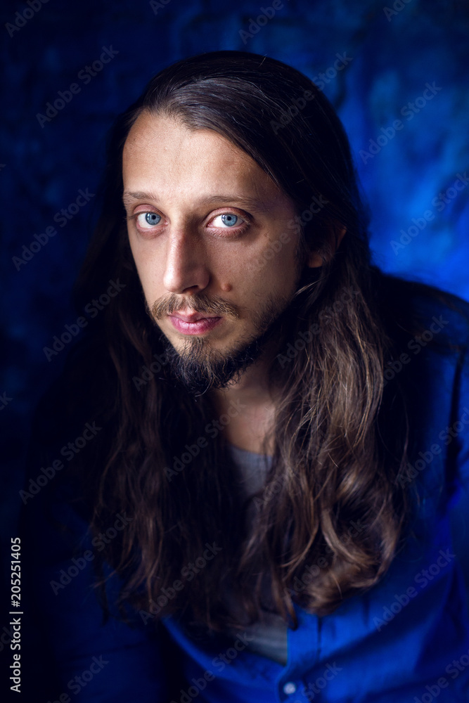 man with long hair and beard sits at home on a chair by the window man with long hair and beard sits at home on a chair by the window