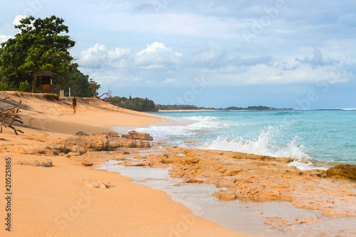 South Asian tropical beach with yellow sand  azure ocean with foamy waves  green trees and colorful blue sky