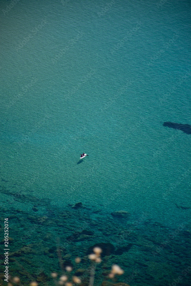 Surfboard on the surface of the water, wonderful blue sea, transparent water in Corfù,  Greece