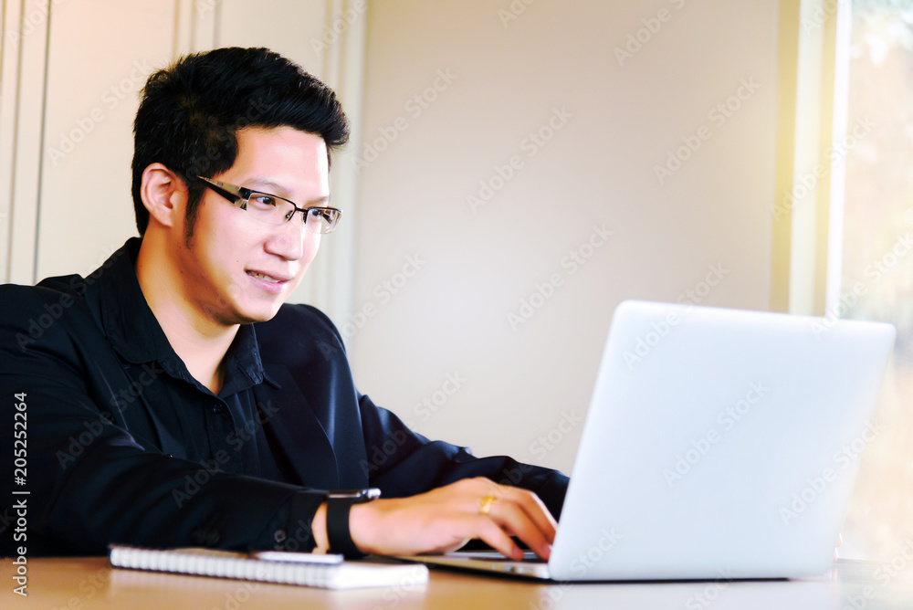 Smart handsome asian businessman in casual suit using laptop and smart phone for working at modern office or coffee shop cafe. Business and Office Concept. Smart handsome asian businessman in casual suit using laptop and smart phone for working at modern office or coffee shop cafe. Business and Office Concept.