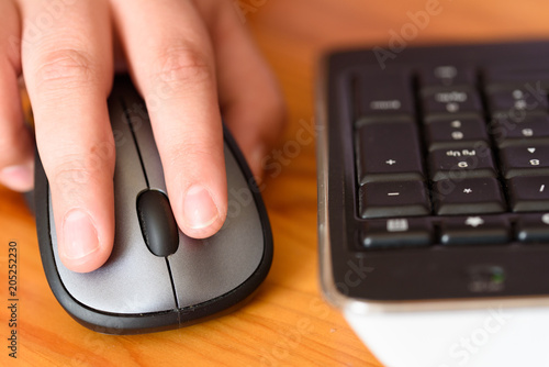 Persons hand using a computer mouse on a wooden desk