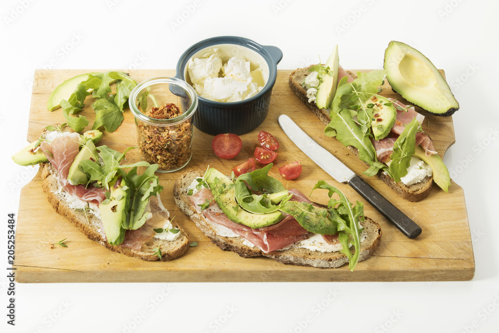 rustikales Zwiebelbrot mit Frischkäse, Parmaschinken, Avocado, Ruccola, Thymian, Chiliraspeln und Tomate, Studio rustikales Zwiebelbrot mit Frischkäse, Parmaschinken, Avocado, Ruccola, Thymian, Chiliraspeln und Tomate, Studio