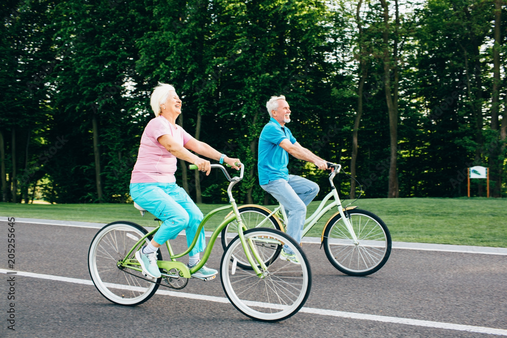 Mature caucasian couple riding bicycle laughing and getting joy from outdoor activities. Retired, active weekend on bicycles