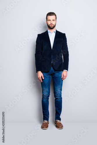 Full size body portrait, snap of attractive trendy teacher with stubble, looking at camera, isolated over grey background, wearing jacket, jeans, shirt