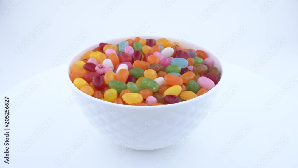 Pile of small bean shaped sugar jelly candies. Rotating in white bowl on the turn table. Isolated. Pile of small bean shaped sugar jelly candies. Rotating in white bowl on the turn table. Isolated.