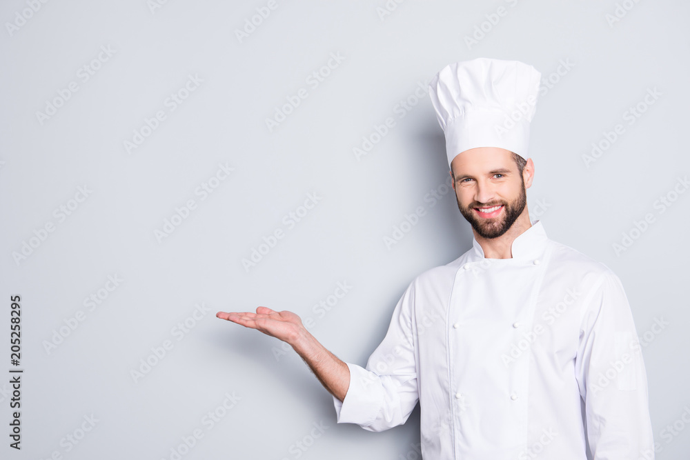Portrait with empty place for advertisement, product of joyful attractive chef cook in beret with stubble holding copy space on his palm, looking at camera, isolated on grey background Portrait with empty place for advertisement, product of joyful attractive chef cook in beret with stubble holding copy space on his palm, looking at camera, isolated on grey background