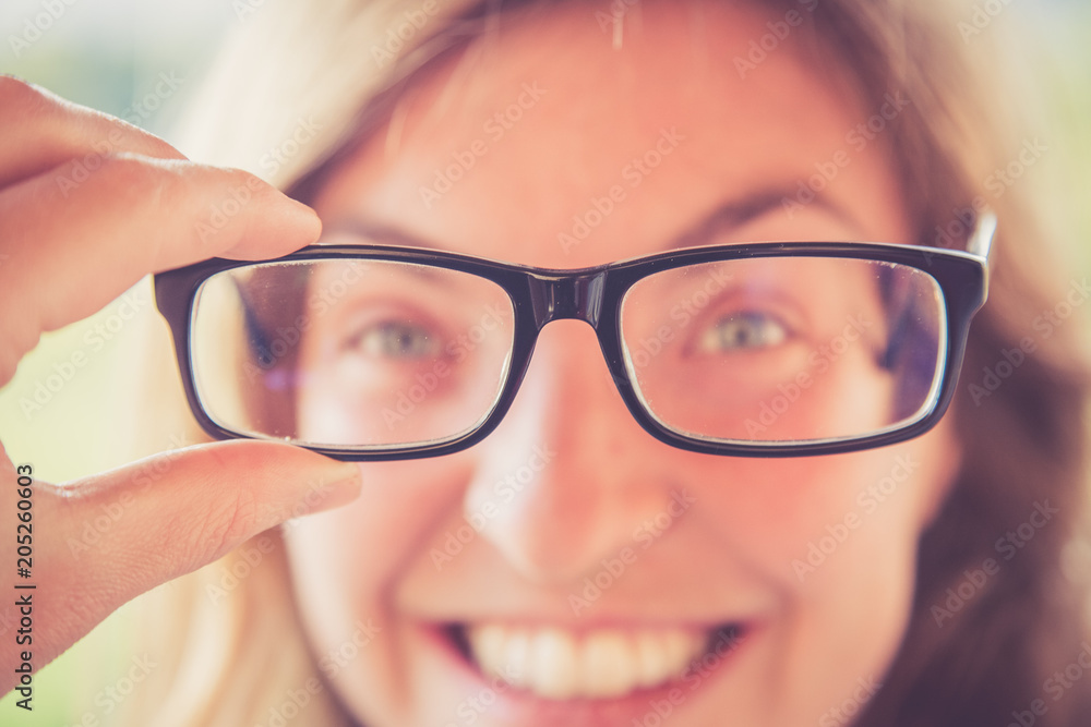 Junger Frau mit Brille vor Gesicht, lächelnd Junger Frau mit Brille vor Gesicht, lächelnd