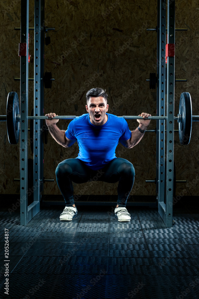 strong man with a barbell makes an effort in the gym, a bodybuilder in training strong man with a barbell makes an effort in the gym, a bodybuilder in training