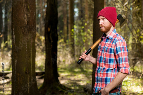 bearded stern forester with an ax walking in the woods
