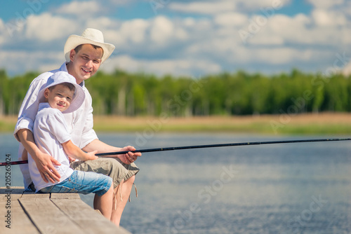 happy men with a fishing rod on a wooden pier while fishing