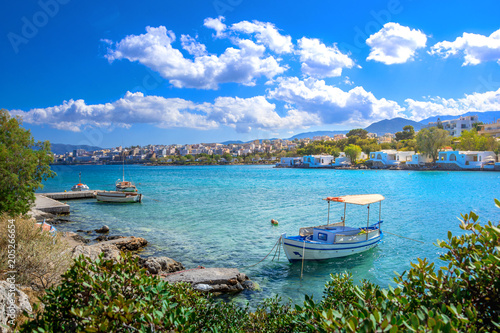 Fototapeta Naklejka Na Ścianę i Meble -  Small natural harbor with anchored fishing boats with the beautiful town of Agios Nikolaos at the background, Crete, Greece.