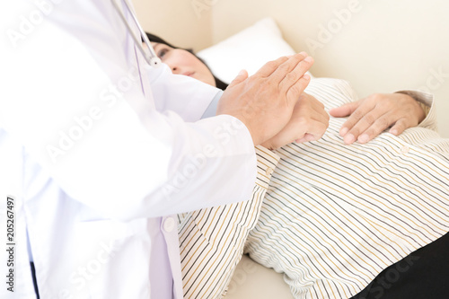 Doctor with patient. Routine health check and holding hands. Male medical doctor with middle age chinese woman.