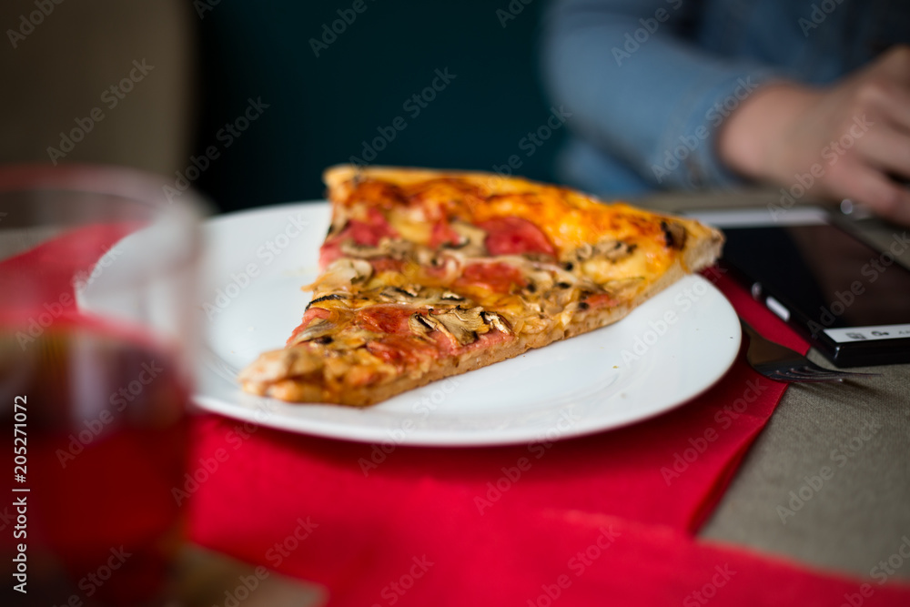A slice of freshly baked italian pizza on a white plate at a restaurant