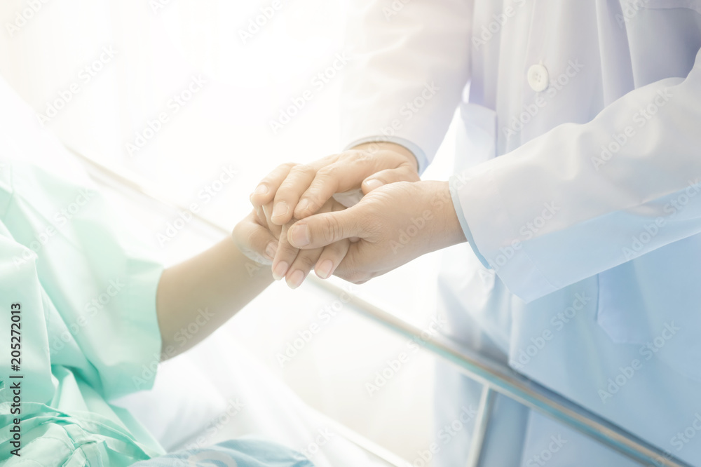 Doctor with patient. Routine health check and holding hands. Male medical doctor with young chinese woman. Doctor with patient. Routine health check and holding hands. Male medical doctor with young chinese woman.