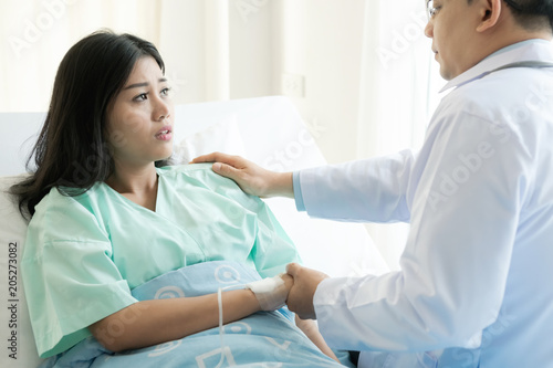 Doctor with patient. Routine health check and holding hands. Male medical doctor with young chinese woman.