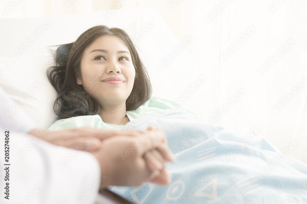Doctor with patient. Routine health check and holding hands. Male medical doctor with young chinese woman. Doctor with patient. Routine health check and holding hands. Male medical doctor with young chinese woman.
