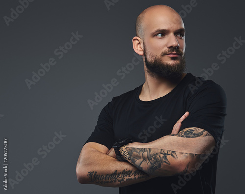 Close-up portrait of a handsome bearded athlete in a black t-shirt, posing with crossed arms in a studio.