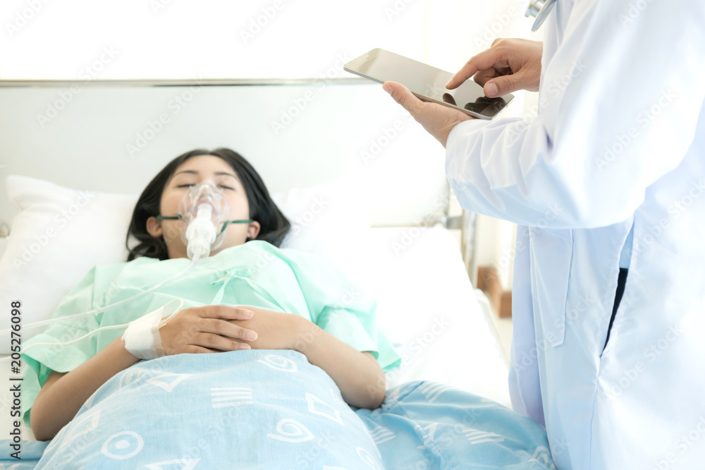 Doctor with patient. Routine health check and taking notes. Male medical doctor with young chinese woman with oxygen mask. Doctor with patient. Routine health check and taking notes. Male medical doctor with young chinese woman with oxygen mask.