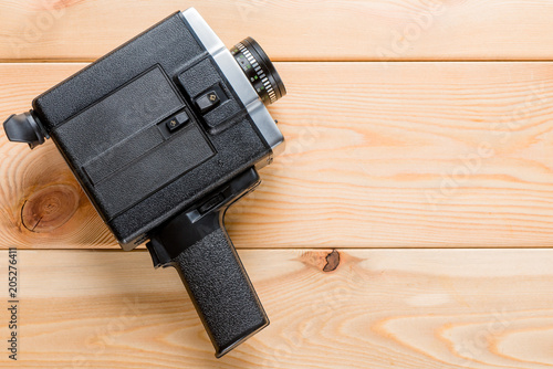 Vintage camcorder rests on light wooden boards, space on the right