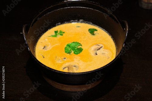 В японском ресторане, желтый суп с грибами в чугунном горшке.