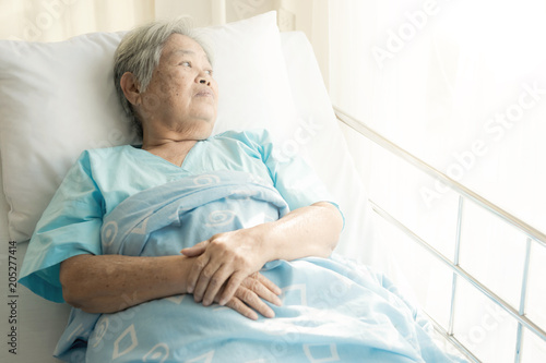 Elderly patient alone in bed. Alone and stress, missing her grand children. Looking at window. Very senior, old chinese woman.