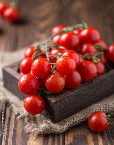 Small red cherry tomatoes on rustic background. Cherry tomatoes on the vine