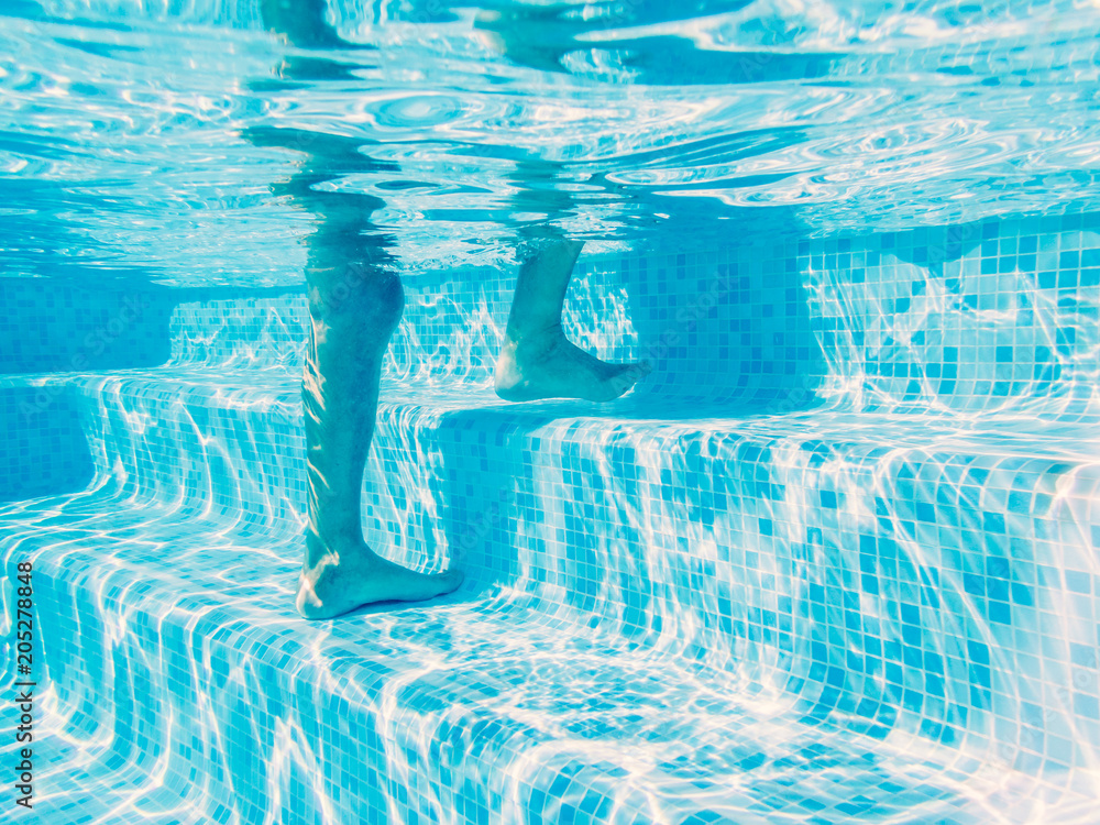Swimming pool steps seen from under the water. A man is climbing the ...