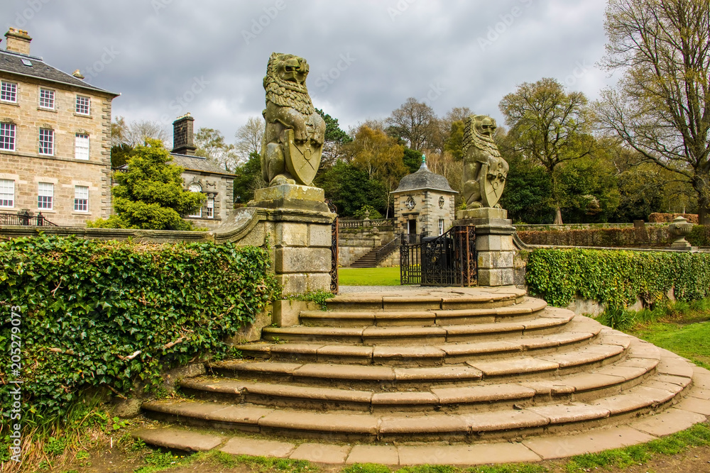 Flight of semi-circular stone steps up to the gateway of a grand country house flanked by stone lions.