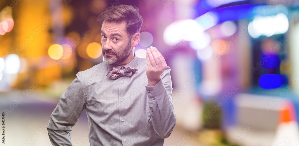 Middle age man, with beard and bow tie angry gesturing typical italian gesture with hand, looking to camera at night club Middle age man, with beard and bow tie angry gesturing typical italian gesture with hand, looking to camera at night club