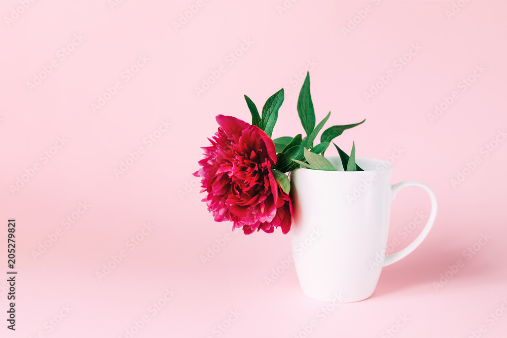 A white cup with pink flower inside. Trendy background with peony.