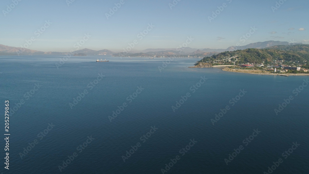 Aerial view: Cargo, Reefer ship in the sea bay. Subic Bay, Philippines, Luzon. Cargo ship in the harbor, against the backdrop of the mountains.