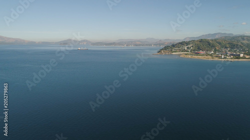 Aerial view: Cargo, Reefer ship in the sea bay. Subic Bay, Philippines, Luzon. Cargo ship in the harbor, against the backdrop of the mountains.