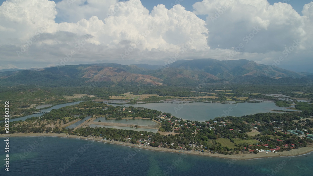 Aerial view of coastline with beach, hotel on the background of mountains. Philippines,Luzon. Tropical landscape, ocean, mountains.