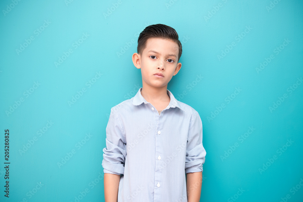 Young boy isolated in blue. Handsome early teenage boy portrait. Cool looking pose. Young boy isolated in blue. Handsome early teenage boy portrait. Cool looking pose.