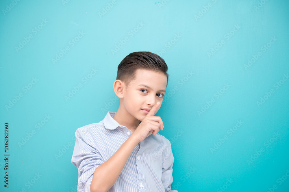 Young boy isolated in blue. Handsome early teenage boy portrait. Happy hush silence pose. Young boy isolated in blue. Handsome early teenage boy portrait. Happy hush silence pose.