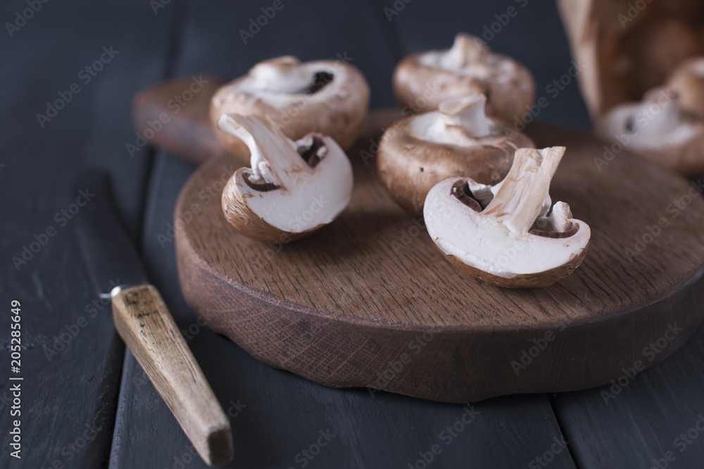 Mushrooms champignons on a wooden board and knife. Ingredients for cooking dinner. Dark photo. Text Mushrooms champignons on a wooden board and knife. Ingredients for cooking dinner. Dark photo. Text
