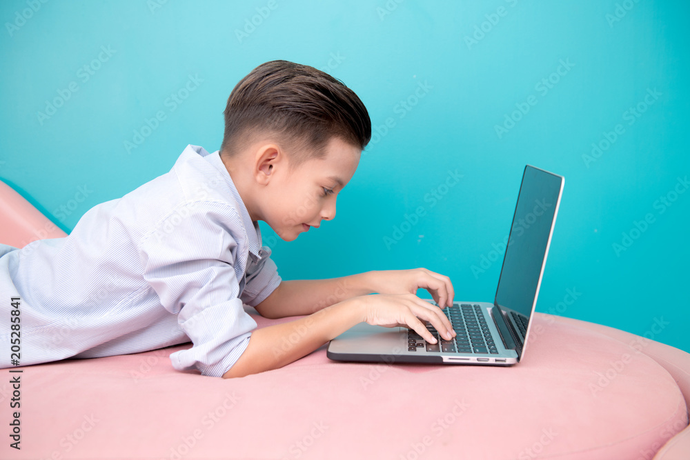 Young software programmer isolated in blue. Handsome early teenage boy portrait. Playing with notebook. Technology concept. Young software programmer isolated in blue. Handsome early teenage boy portrait. Playing with notebook. Technology concept.