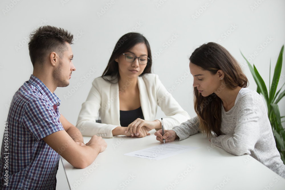 Young wife signing divorce papers, Asian lawyer watching her making break up decision, husband observing lover reaction. Concept of documenting legal separation, unsuccessful marriage, dissolution