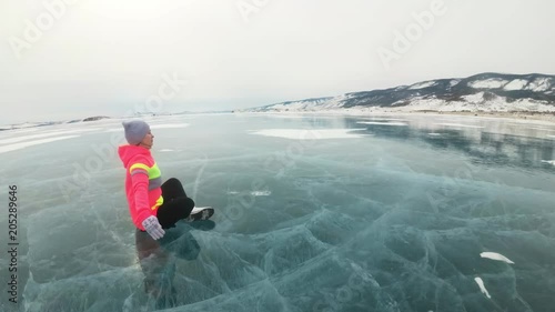 Girl is training practice yoga in winter. Woman is do stretching and meditation on ice in nature. Athlete practices yoga on beautiful with cracks ice. Woman do sport fitness in outdoor. Background photo