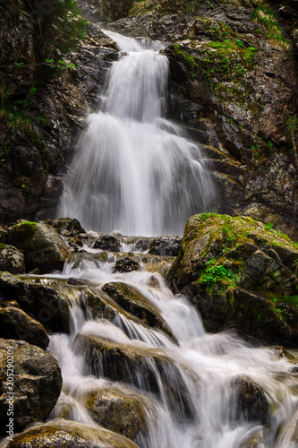 Scenic waterfall flows through the wilderness in the mountains.