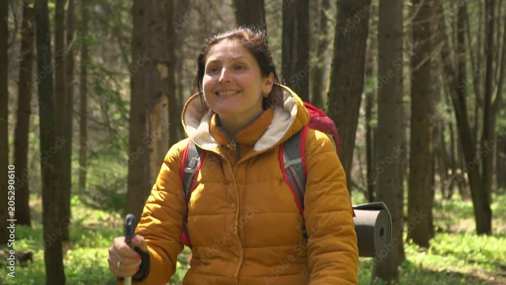 120 fps. The woman with a red backpack travels around the forest road. Scandinavian walking. 120 fps. The woman with a red backpack travels around the forest road. Scandinavian walking.