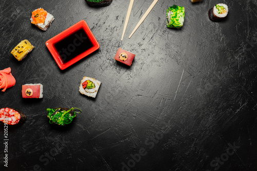 Top view of Japanese Sushi and chopsticks on black background. Sushi rolls, nigiri, maki, pickled ginger, wasabi, soy sauce. Space for text. Top view. Sushi background. food frame