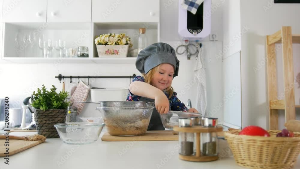 Preschool girl baker sifts flour in a bowl for cooking biscuits Preschool girl baker sifts flour in a bowl for cooking biscuits