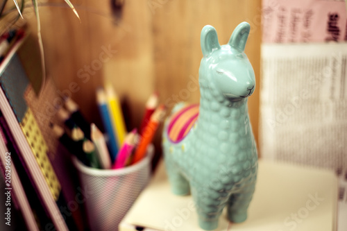 Figure of llama on a work table with books and pencils, back to school concept