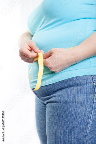 fat woman measuring her stomach (overweight, obesity). Isolated on white background.